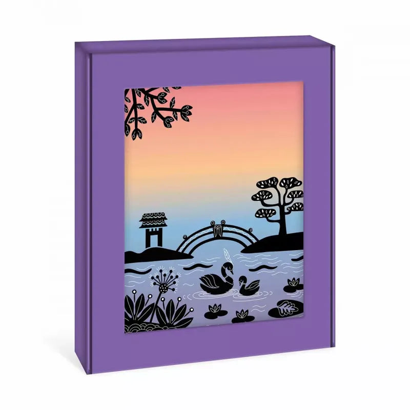 The Janod Sunset Lover is a colorful picture book with a purple cover featuring an illustration of two swans swimming in a pond, framed by plants and trees. A bridge with two birds on it, a water well, and a sunset gradient sky are in the background, reminiscent of a children's art kit sunset painting craft.