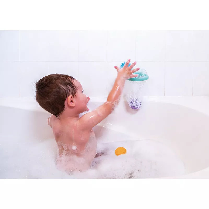 A young boy playing with the Janod Tacti'Basket Bath Toy in a bathtub filled with water.