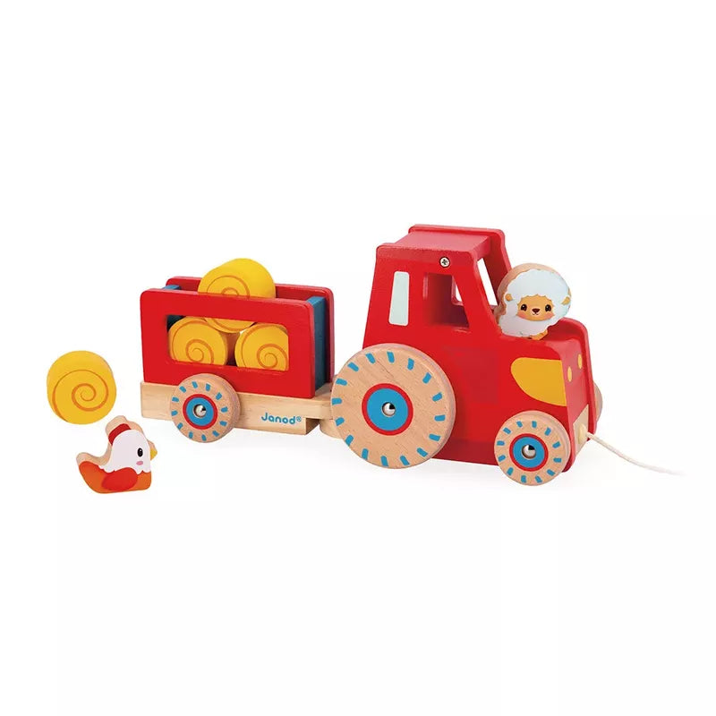 The Janod Farm Pull Along Tractor is a colorful wooden toy with a red engine, blue wheels, a yellow cargo bed containing a single yellow piece, and a happy little peg figure driver, accompanied by small red and white bird accessories.