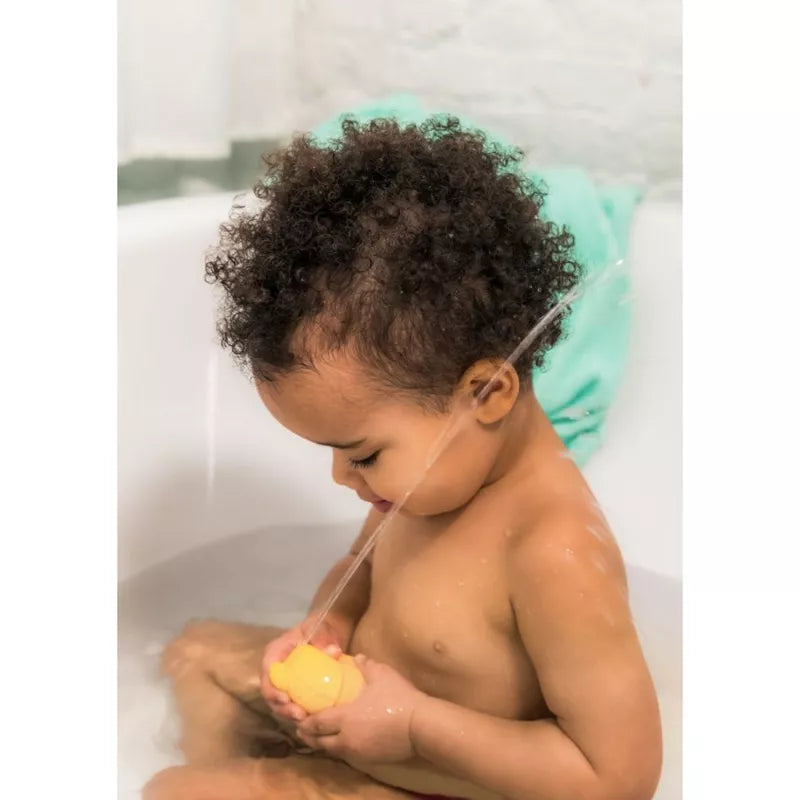 A baby sitting in a bathtub holding a Lilliputiens Gaspard Water sprinkler.