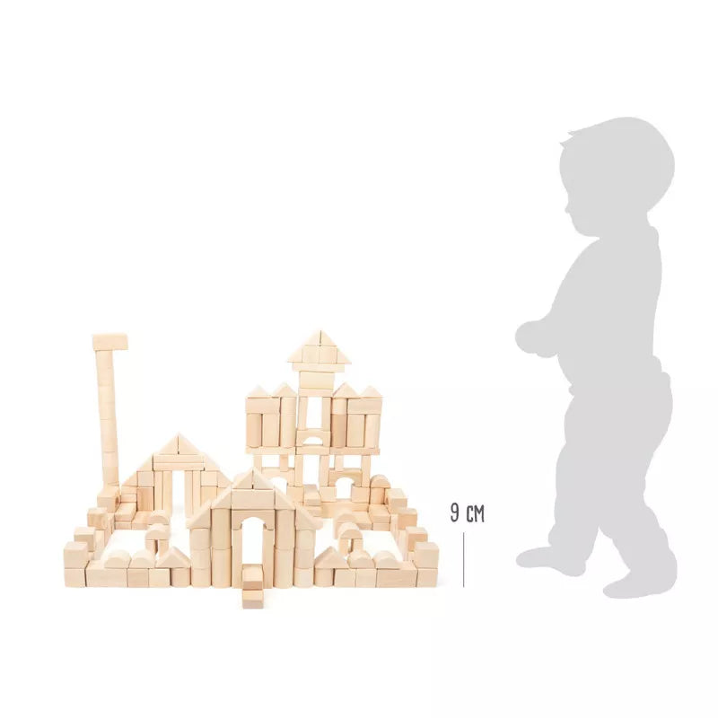 A Natural Wooden Building Blocks (200) set with a child standing next to it.