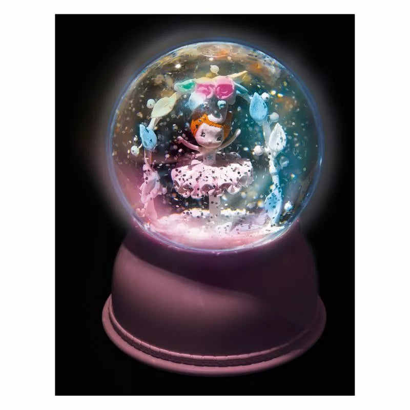 A Djeco Snow Ball Nightlight Ballerina with a little girl inside of it.