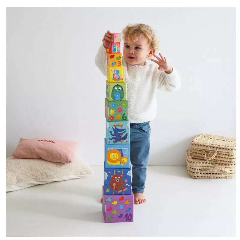 A young child is playing with a tower of Djeco Blocks Rainbow.