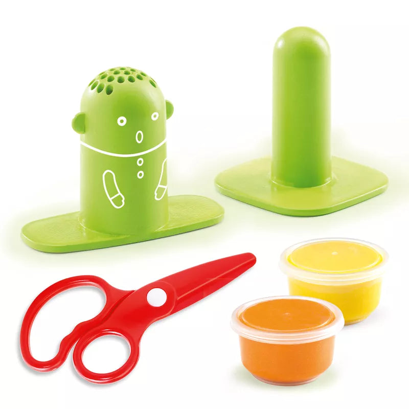 A green Djeco Playdough Hairdressing set with scissors, a cup, and a container.